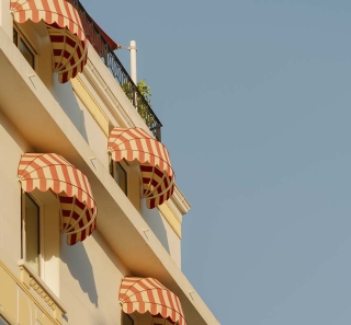 Fa&ccedil;ade de l&rsquo;h&ocirc;tel Edgar Suites &agrave; Cannes avec marquises ray&eacute;es typiques de l&rsquo;architecture m&eacute;diterran&eacute;enne