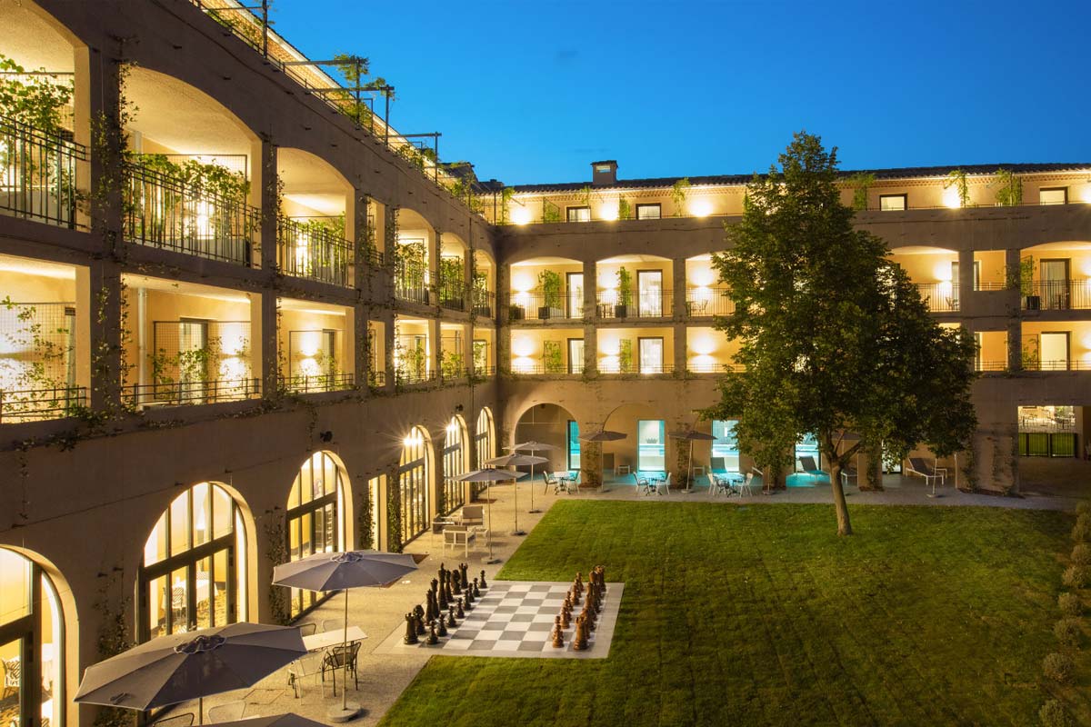 Cour intérieure de l’Hôtel du Roi à Carcassonne avec architecture éclairée et terrasse paysagée au cœur de l’établissement
