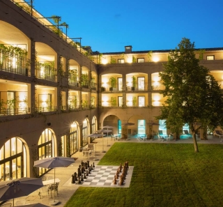 Cour int&eacute;rieure de l&rsquo;H&ocirc;tel du Roi &agrave; Carcassonne avec architecture &eacute;clair&eacute;e et terrasse paysag&eacute;e au c&oelig;ur de l&rsquo;&eacute;tablissement
