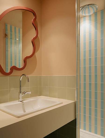 Salle de bain de l’hôtel Edgar Suites à Cannes avec carrelage rayé et miroir décoratif