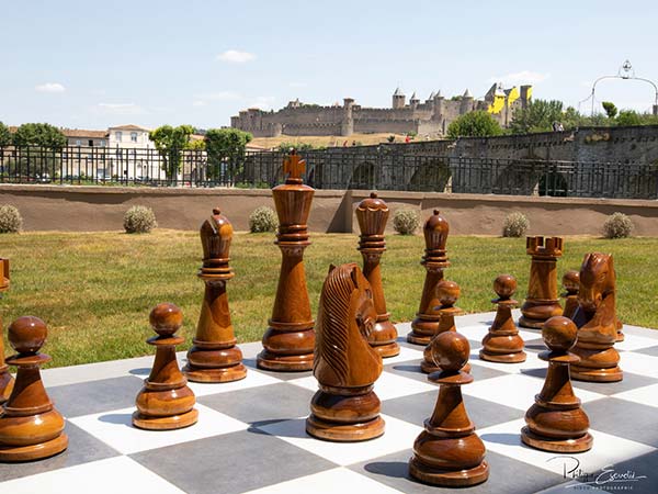 Échiquier géant en carrelage sur la terrasse de l’Hôtel du Roi avec la cité de Carcassonne en arrière-plan