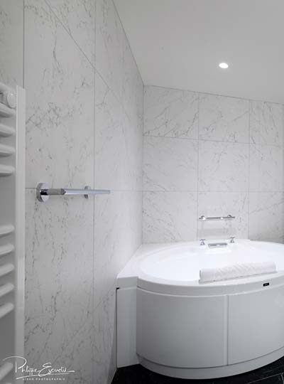 Salle de bain avec baignoire ronde et carrelage céramique effet marbre à l’Hôtel du Roi à Carcassonne