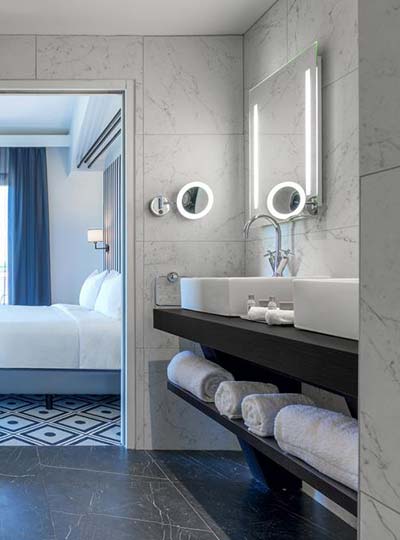 Salle de bain avec vasques et carrelage céramique effet marbre dans une chambre de l’Hôtel du Roi à Carcassonne