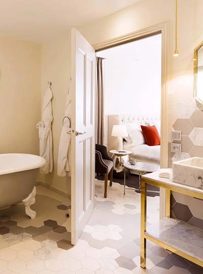 Salle de bain d’hôtel avec carrelage hexagonal en grès cérame et pierre naturelle coordonnée avec la chambre
