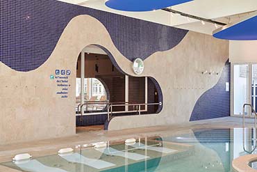 Architecture intérieure de la piscine du Mercure Quiberon avec mosaïque bleue et grès cérame aspect pierre