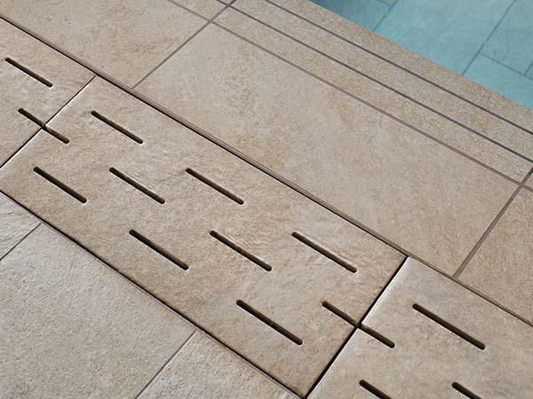 Sol en grès cérame aspect pierre avec dalles techniques autour de la piscine du Spa NUXE Mercure Quiberon