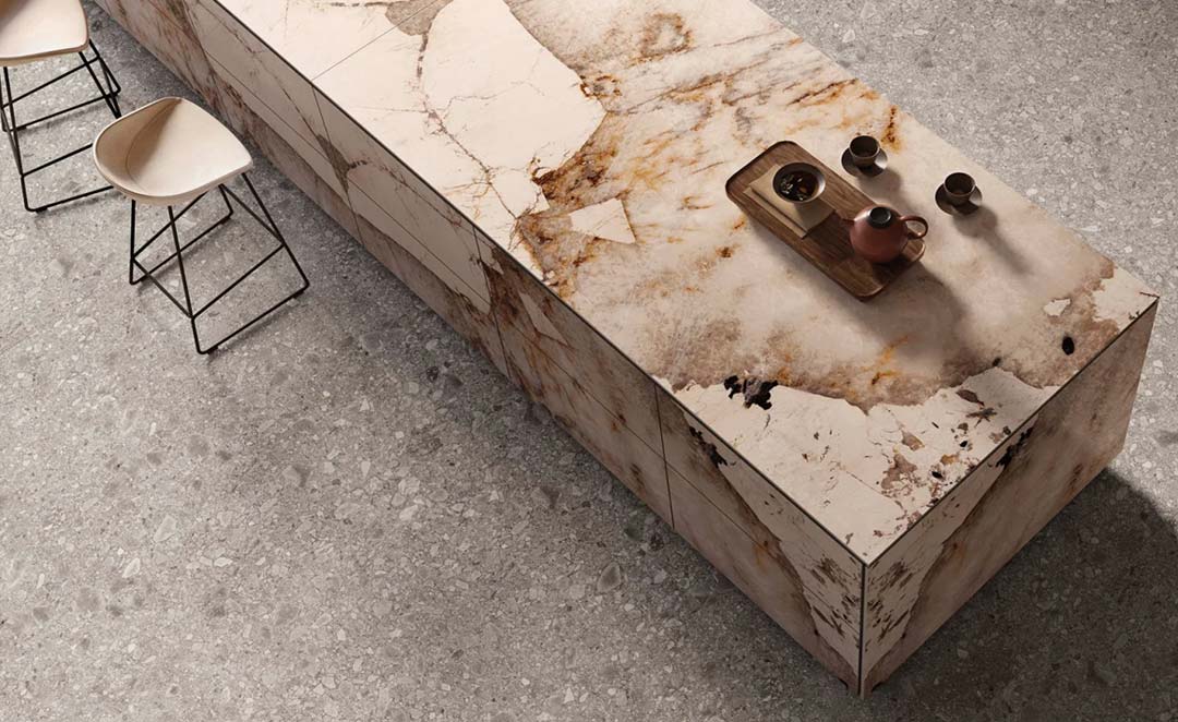 Dalle céramique XXL effet pierre naturelle utilisée en îlot de cuisine contemporain avec veinage minéral et surface texturée élégante