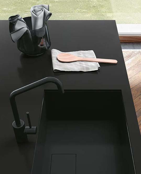 Dalles céramiques XXL effet résine sur plan de travail sombre avec surface mate continue et esthétique contemporaine épurée