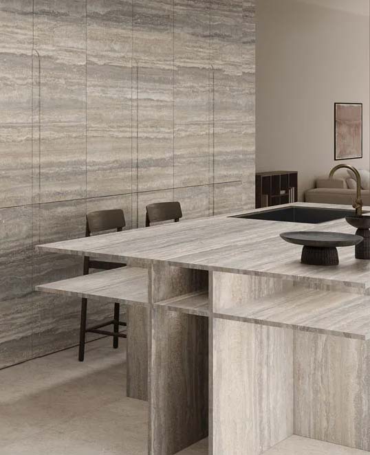 Dalles céramiques XXL effet pierre travertin en cuisine contemporaine avec surfaces minérales continues et intégration architecturale naturelle