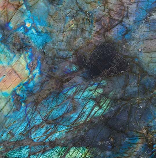 Gros plan de céramique effet labradorescence, veines minérales et reflets bleus changeants selon la lumière