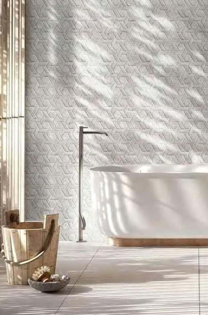 Mosaïque géométrique blanche pour ambiance spa contemporaine Mosaïque géométrique blanche en relief habillant un mur de salle de bain contemporaine et lumineuse