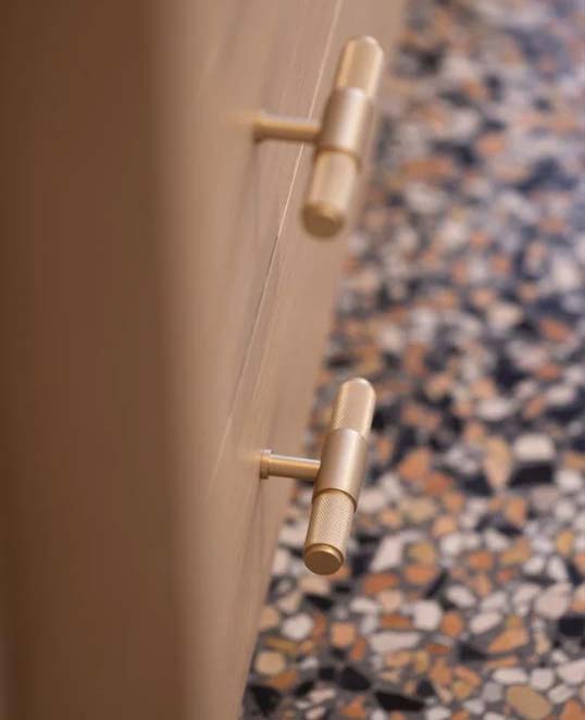 Sol en terrazzo et mobilier bois aux finitions laiton Détail d’un sol en terrazzo minéral multicolore avec mobilier en bois et poignées en laiton