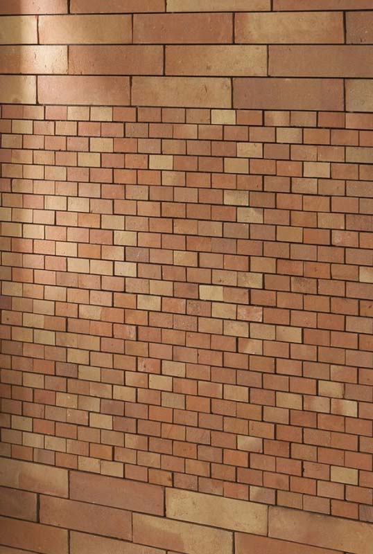 Durabilité et polyvalence de la terre cuite en architecture Mur en briques de terre cuite artisanale aux teintes naturelles posé en appareillage régulier pour intérieur et extérieur